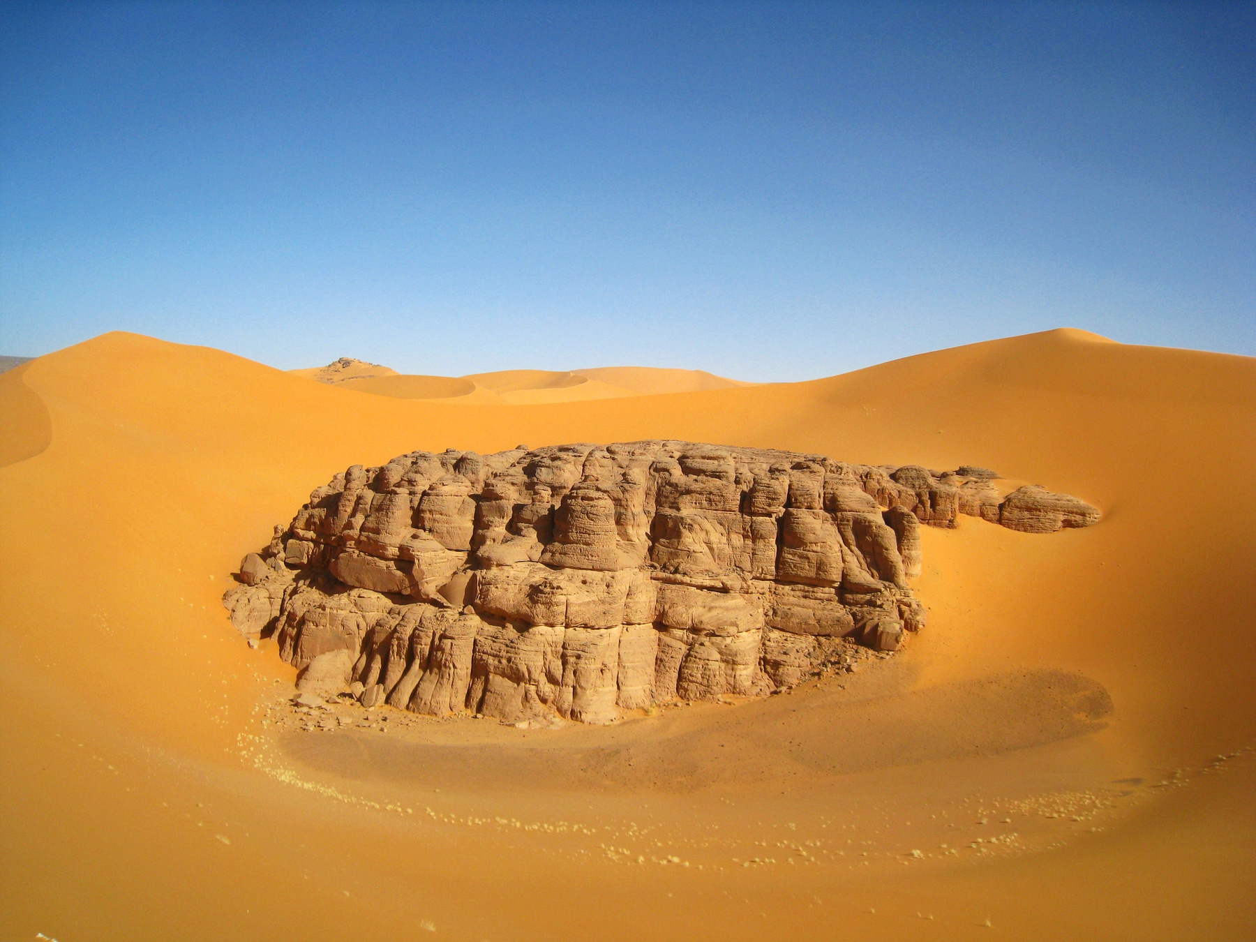 Сахара наступает, и высокие песчаные дюны потихонечку засыпают древние скалы нагорья Тадрат. Алжир пейзаж скалы