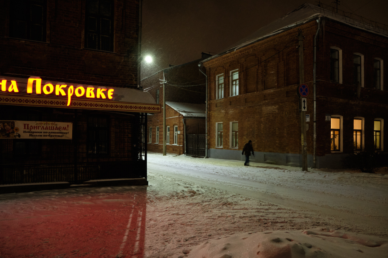 Одинокий прохожий вечер улица снег здания окна фонарь прохожий