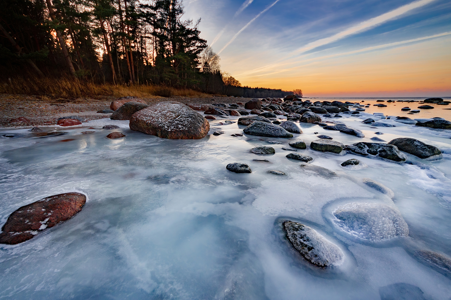 Замёрзший прибой море вода камни закат золотой час небо цвета лёд